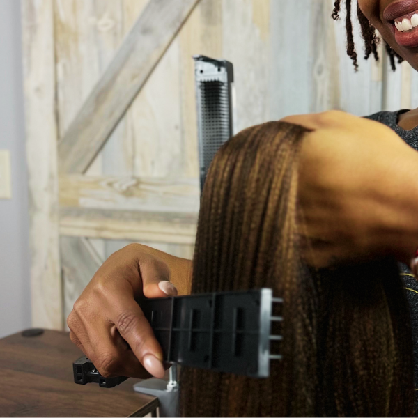 Close-up of a Nadra Smiley using the Alli Styles Assistant to securely hold bulk braiding hair, demonstrating a prep-free experience for faster setup and efficient sectioning.